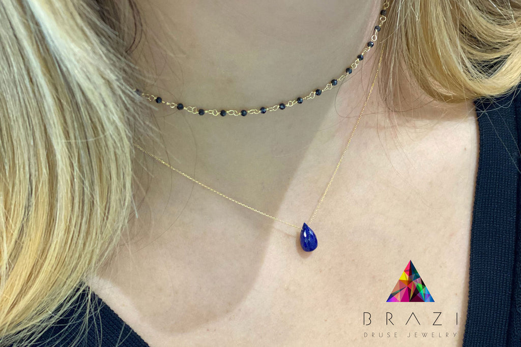 Złoty naszyjnik z kroplą lapis lazuli na szyi modelki, biżuteria Brazi w stylizacji kaskadowej