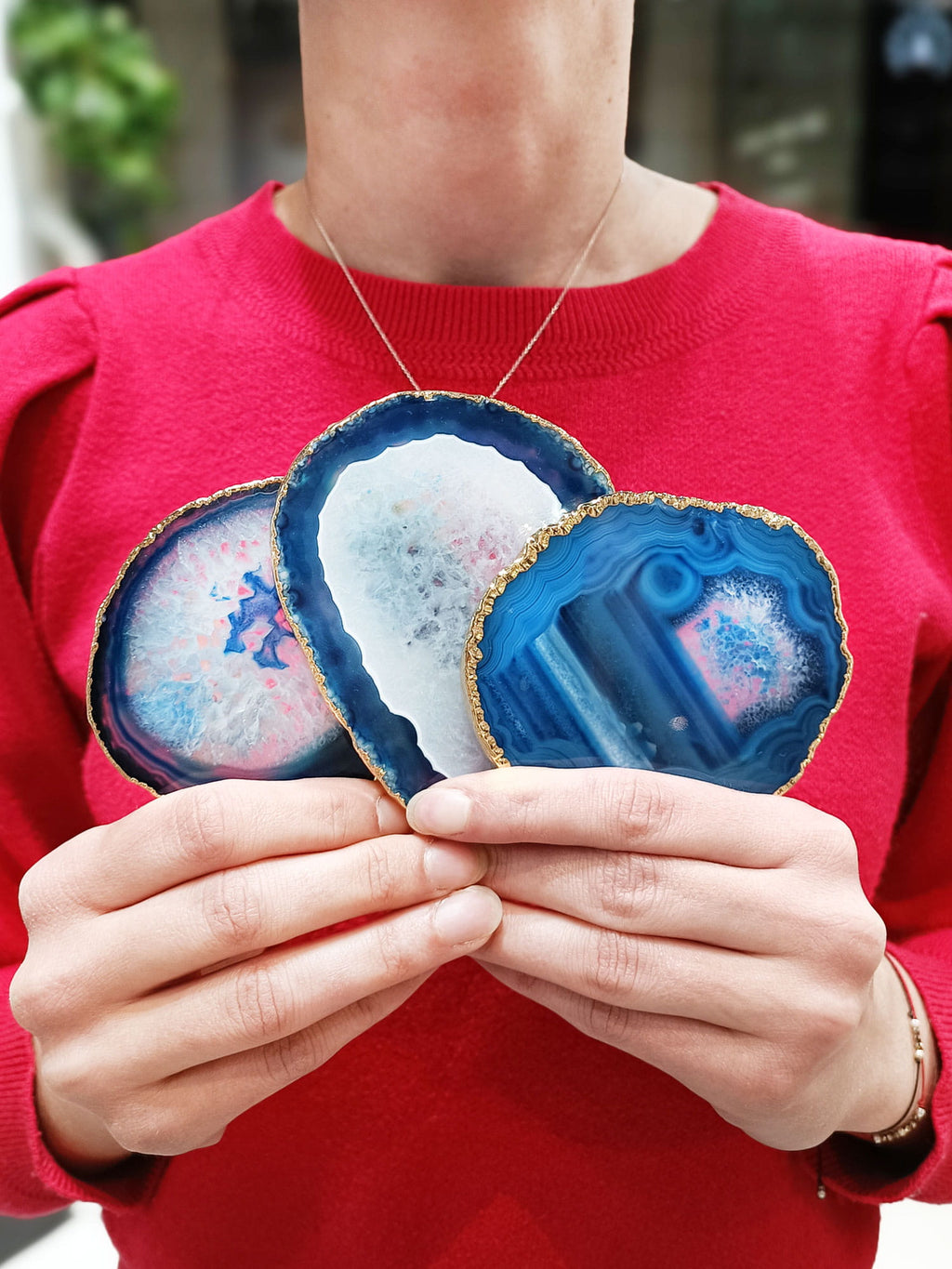 Trzy podstawki z naturalnego agatu trzymane w dłoniach, niebieskie plastry ze złotym brzegiem Brazi.