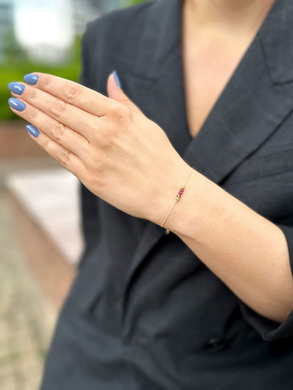Bransoletka z kamieni naturalnych na nadgarstku kobiety w czarnej marynarce, biżuteria Brazi