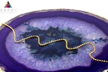 Złoty naszyjnik z zawieszką lilijką na plastrze fioletowego agatu, biżuteria Brazi.