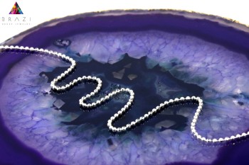 Srebrny łańcuszek o splocie kulkowym na plastrze fioletowego agatu.