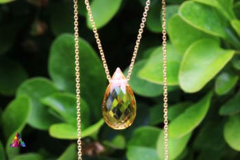 Naszyjnik z cytrynem w formie kropli na złotym łańcuszku, biżuteria Brazi na tle liści.