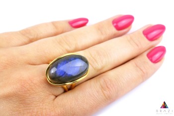 Pierścionek z owalnym labradorytem na dłoni, złocona biżuteria z naturalnych kamieni Brazi.