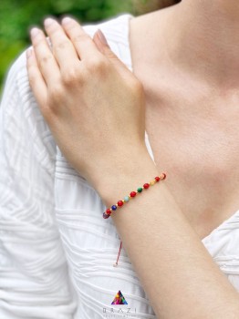 Bransoletka z czerwonym koralem i zestawem minerałów na nadgarstku modelki, ręcznie pleciona biżuteria Brazi