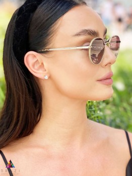 Złote kolczyki z kryształem górskim o trójkątnym szlifie w stylizacji lifestyle, biżuteria Brazi.