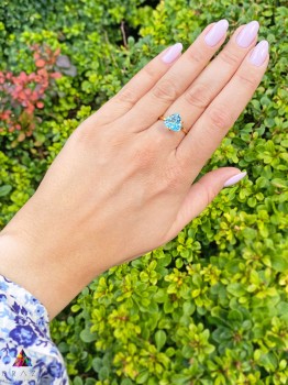 Pierścionek z topazem sky blue o szlifie trylion w oprawie z żółtego złota, biżuteria Brazi na tle natury.