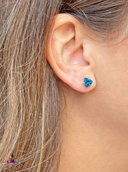 Kolczyk z topazem London Blue o szlifie trylion na uchu, biżuteria Brazi z kamieni naturalnych.