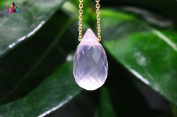 Makrofotografia fasetowanego kwarcu różowego w złotej oprawie na tle liści, biżuteria Brazi