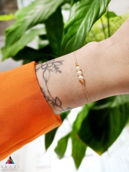 Bransoletka z naturalnymi perłami na beżowym sznurku, biżuteria Brazi prezentowana na nadgarstku.