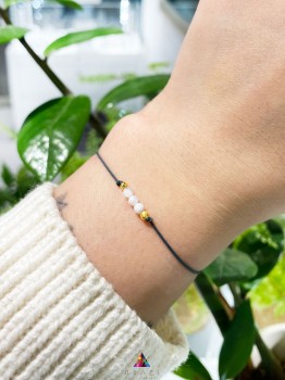 Bransoletka z naturalnym kamieniem księżycowym na szarym sznurku na nadgarstku modelki, marka Brazi