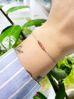 Bransoletka z naturalnym różowym turmalinem na szarym sznurku prezentowana na nadgarstku, marka Brazi.