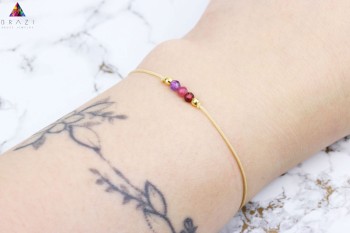 Bransoletka z naturalnych minerałów na nadgarstku, czarny sznurek i pozłacane elementy, biżuteria Brazi