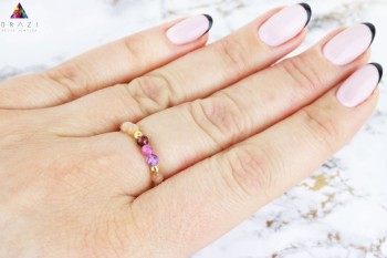 Elastyczny pierścionek z naturalnych kamieni na dłoni modelki, jasne marmurowe tło, marka Brazi