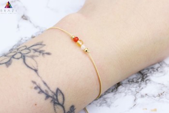 Bransoletka z naturalnymi kamieniami w kolorze czerwonym, żółtym i transparentnym na nadgarstku, biżuteria Brazi