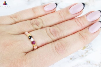 Pierścionek z koralików z czarnym i białym kamieniem na dłoni, złote elementy wykończeniowe, marka Brazi.