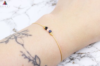 Bransoletka z naturalnych kamieni na ciemnym sznurku, zbliżenie na nadgarstku, biżuteria Brazi