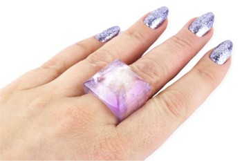 Srebrny pozłacany pierścionek z naturalnym fioletowym ametystem na dłoni modelki.