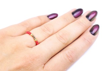 Pierścionek z czerwonym koralem i pirytem na palcu, biżuteria Brazi prezentująca skalę i naturalne odcienie kamieni