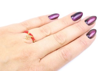 Pierścionek z naturalnym koralem i złotą koniczynką na dłoni modelki, biżuteria Brazi