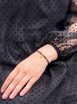 Bransoletka z czarnym turmalinem i złotą zawieszką na nadgarstku modelki, marka Brazi