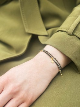 Podwójna bransoletka z naturalnym pirytem i złotymi lilijkami na nadgarstku modelki, biżuteria marki Brazi.