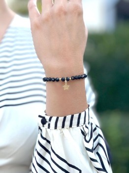 Bransoletka z czarnym turmalinem i złotą zawieszką gwiazdką na nadgarstku, biżuteria Brazi.