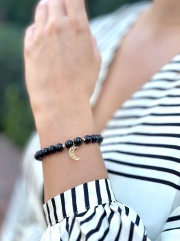 Bransoletka z czarnego turmalinu i złotą zawieszką księżyc na nadgarstku modelki, biżuteria Brazi