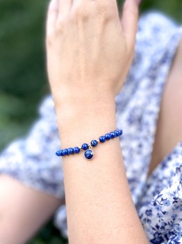 Bransoletka z kamieni lapis lazuli ze złoconą zawieszką na nadgarstku modelki, biżuteria Brazi