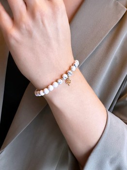 Bransoletka z naturalnego howlitu i złotej koniczynki na nadgarstku, biżuteria Brazi