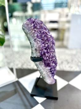 Naturalny ametyst na czarnym stojaku, widok z boku ukazujący strukturę surowej bryły, dekoracja wnętrz Brazi.
