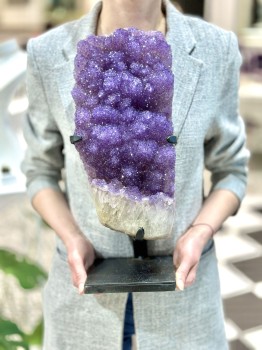 Szczotka ametystu na czarnej podstawce trzymana w dłoniach, naturalna dekoracja z minerałów Brazi