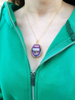 Fioletowy naszyjnik z agatem Brazi na modelu, prezentacja biżuterii na tle zielonej bluzy.