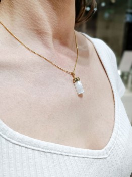 Złocony naszyjnik z małym, surowym selenitem prezentowany na dekolcie modelki, marka Brazi