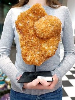 Szczotka cytrynu na podstawce trzymana w dłoniach, prezentacja wielkości naturalnego kryształu marki Brazi.