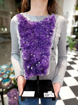 Duża szczotka ametystu na czarnej podstawie trzymana w dłoniach, naturalna dekoracja od Brazi