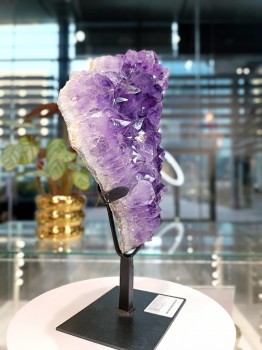 Szczotka naturalnego ametystu na czarnej podstawce, widok z boku ukazujący warstwową strukturę minerału, Brazi.