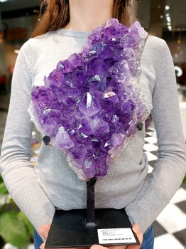 Duża szczotka ametystu na podstawce trzymana w dłoniach, naturalny minerał dekoracyjny z Brazylii, Brazi.