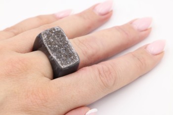 Pierścionek z czarnego agatu z druzą o surowej fakturze prezentowany na dłoni, biżuteria marki Brazi