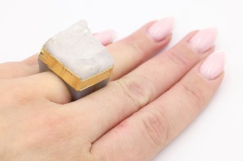 Pierścionek z naturalnym kryształem górskim na dłoni, złota oprawa i szara obrączka Brazi