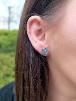 Złocone kolczyki z naturalną niebieską druzą agatu prezentowane na uchu modelki, marka Brazi.