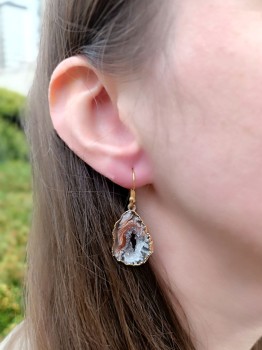 Kolczyk z plastra agatu w złoconej oprawie prezentowany na uchu modelki, naturalny minerał marki Brazi