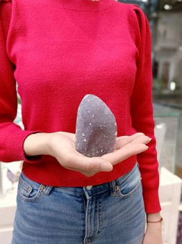 Bryłka naturalnego ametystu tęczowego trzymana w dłoniach, prezentacja wielkości kamienia Brazi.