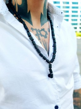 Zbliżenie na męski naszyjnik z matowego turmalinu na tle białej koszuli z krawatką, biżuteria Brazi