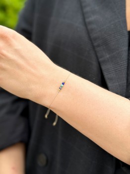 Zbliżenie na bransoletkę z kolorowych minerałów na jasnym sznurku, ręcznie wykonana biżuteria Brazi