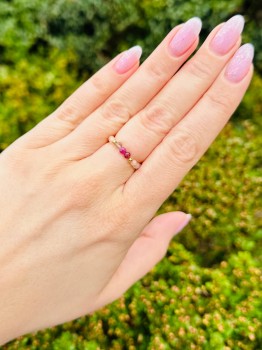 Pierścionek z szarym i różowym kamieniem na dłoni, biżuteria z koralików z pozłacanymi detalami, marka Brazi.