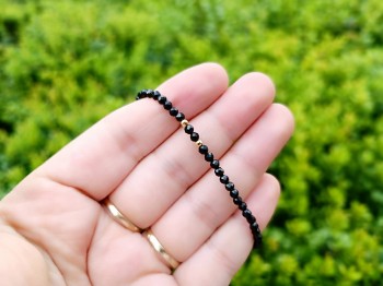 Zbliżenie na fasetowane koraliki czarnego turmalinu w bransoletce ze złotymi dodatkami, Brazi