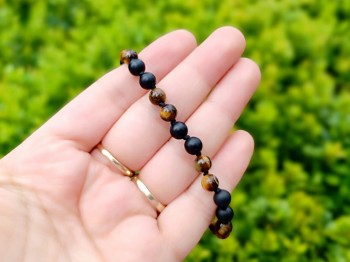 Detal naturalnych koralików tygrysiego oka i czarnego turmalinu w świetle dziennym, biżuteria Brazi