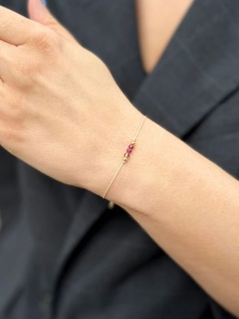 Bransoletka z szarym, różowym i bordowym minerałem przy rękawie ciemnej marynarki, marka Brazi