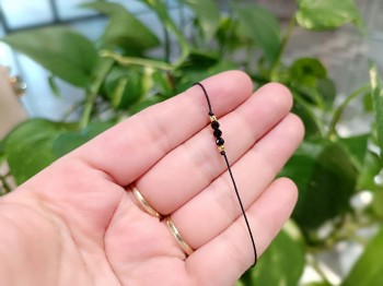 Zbliżenie na fasetowane czarne turmaliny i złote przekładki w bransoletce sznurkowej, marka Brazi