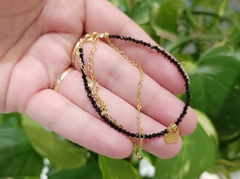 Zbliżenie na czarny turmalin fasetowany i złoty łańcuszek w bransoletce z sercem, biżuteria Brazi.